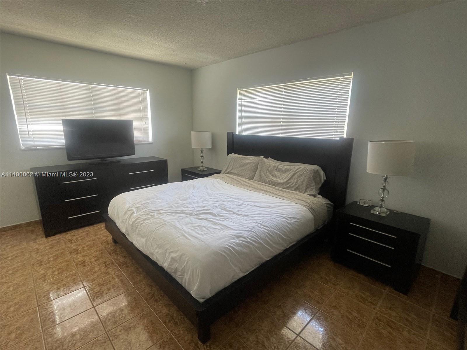 1420 Atlantic Shores Boulevard, Unit 326 Hallandale Beach, FL 33009 - Photo 13 of 16 a bedroom with a bed and a flat screen tv