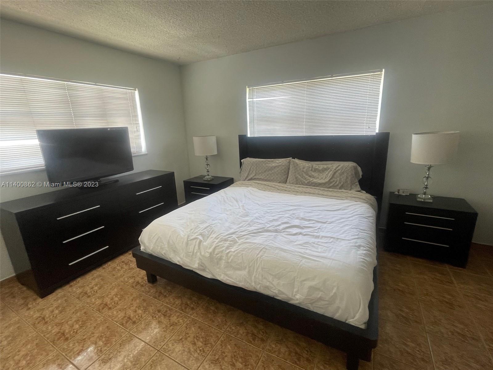 1420 Atlantic Shores Boulevard, Unit 326 Hallandale Beach, FL 33009 - Photo 10 of 16 a bedroom with a bed and a flat screen tv