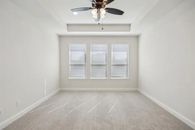 an empty room with a chandelier fan and windows