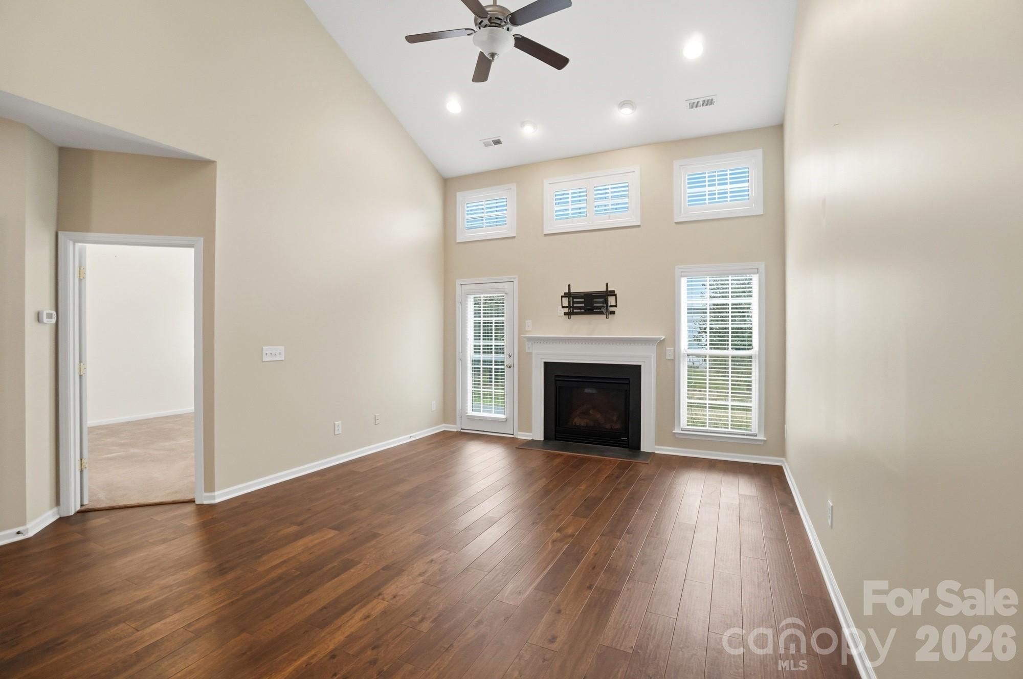 284 Garnet Court Fort Mill, SC 29708 - Photo 16 of 42 an empty room with wooden floor a fireplace and windows