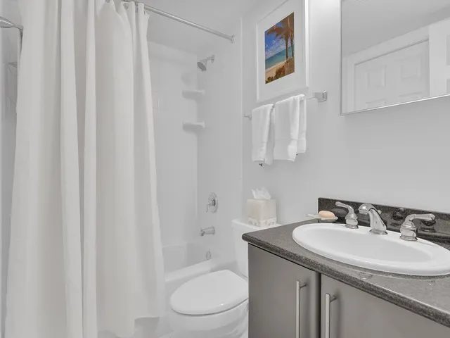 a bathroom with a granite countertop sink toilet and a mirror