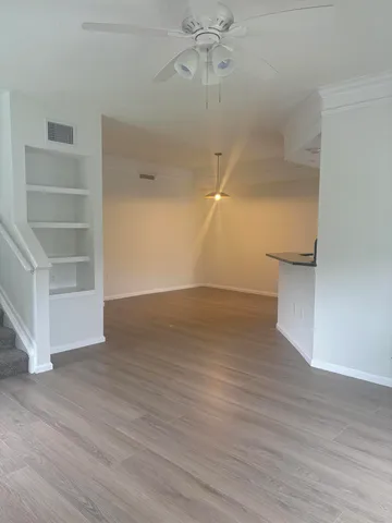 an empty room with wooden floor and ceiling fan
