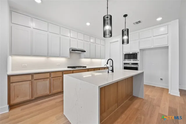 a kitchen with stainless steel appliances granite countertop a sink a stove and a refrigerator