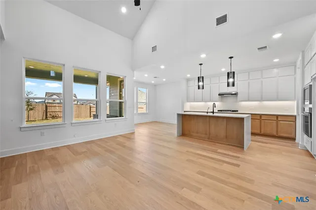a view of kitchen with stainless steel appliances kitchen island a large counter top and a wooden floors