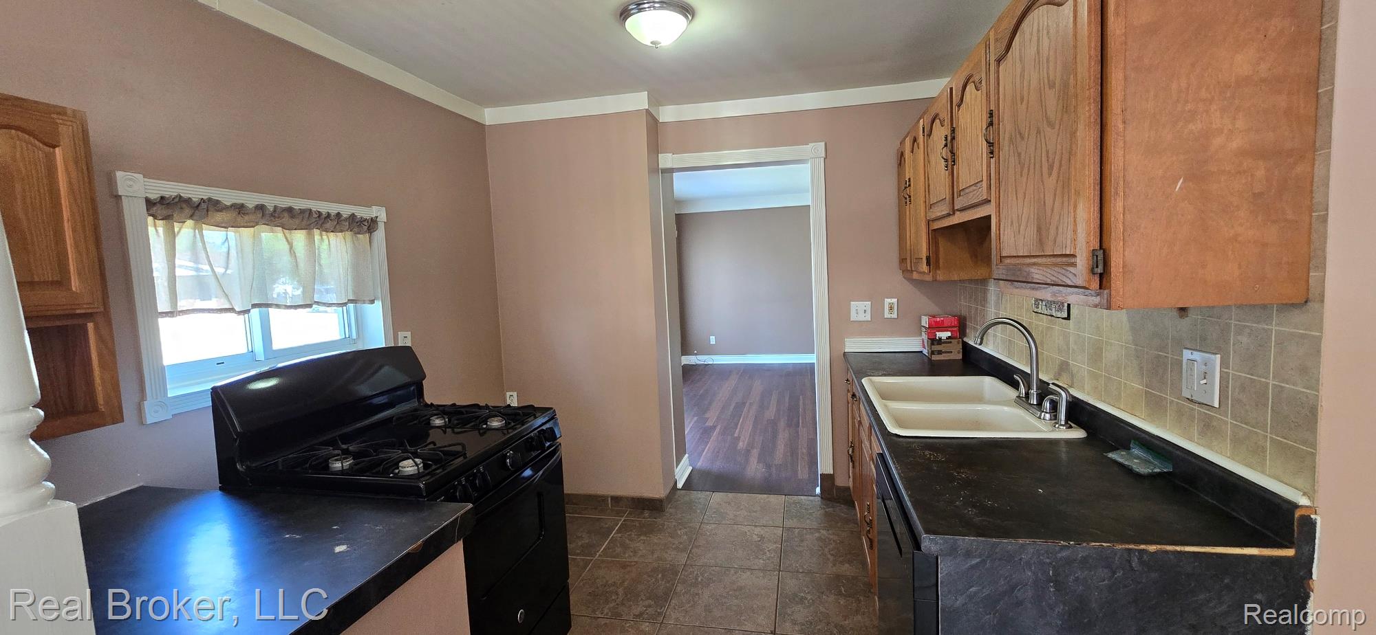 23401 Filmore Street Taylor, MI 48180 - Photo 15 of 16 Kitchen featuring wood cabinetry, a dual-basin sink with a stainless steel faucet, and a black gas range