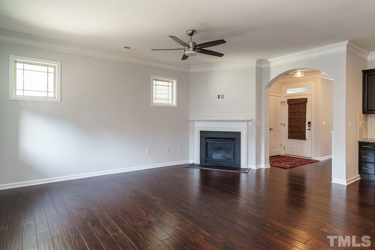 1340 Rodessa Run Raleigh, NC 27607 - Photo 11 of 28 an empty room with wooden floor fireplace and windows