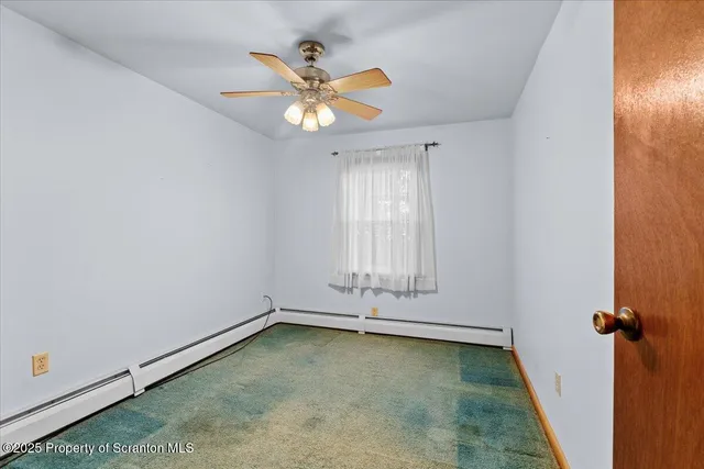 an empty room with chandelier fan and windows