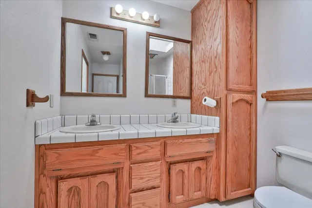 a bathroom with a granite countertop sink toilet and mirror