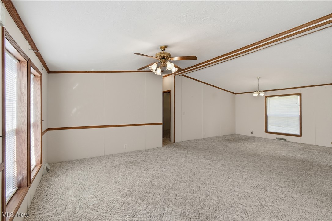 60602 Shaw Road Cambridge, OH 43725 - Photo 22 of 41 Unfurnished room featuring crown molding, light colored carpet, ceiling fan, a chandelier, and a decorative wall