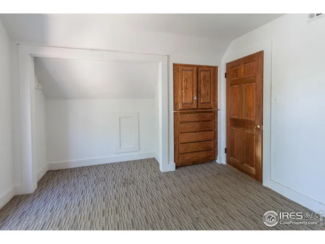 a view of an empty room with closet and wooden floor