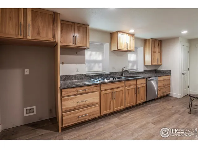 a kitchen with granite countertop a stove cabinets and wooden floor