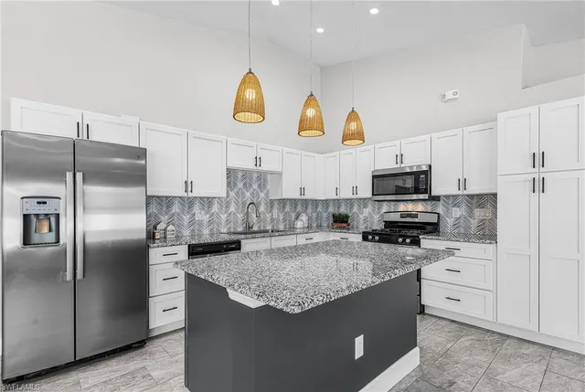 a kitchen with stainless steel appliances granite countertop a sink a stove a refrigerator a center island and cabinets