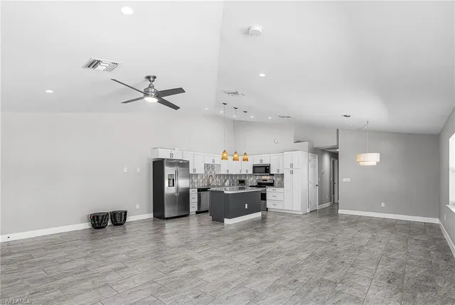 a view of a kitchen with refrigerator and wooden floor