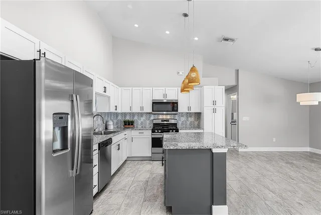 a kitchen with stainless steel appliances granite countertop a refrigerator and a stove top oven