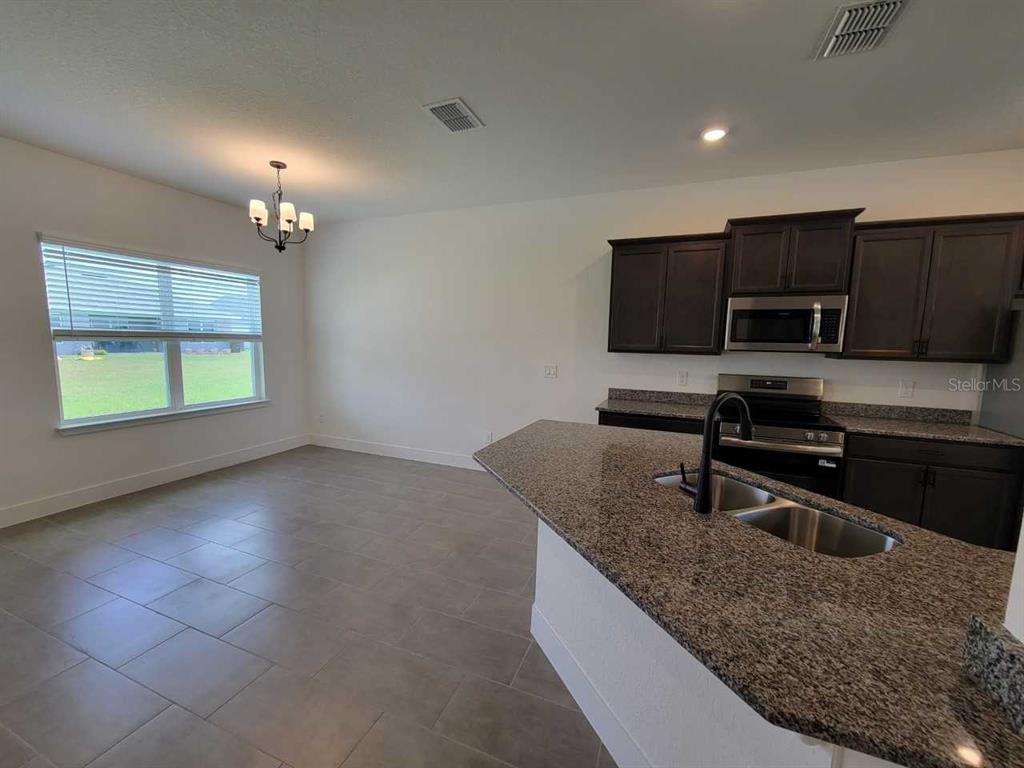 4380 Southwest 92nd Pl Road Ocala, FL 34476 - Photo 11 of 57 a kitchen with kitchen island granite countertop a sink stove and microwave