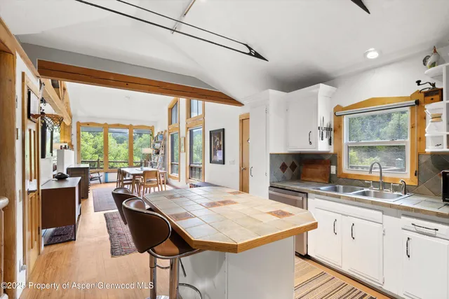 a dining hall with stainless steel appliances granite countertop a stove top oven a dining table and chairs with the floor to ceiling window