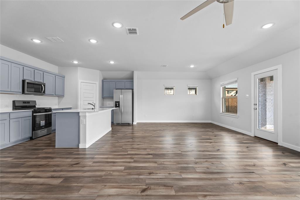 718 Parkside Drive Lavon, TX 75166 - Photo 21 of 22 Kitchen with stainless steel appliances, open floor plan, a kitchen island with sink, recessed lighting, and dark wood finished floors