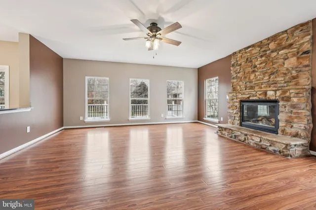 an empty room with wooden floor fireplace and windows