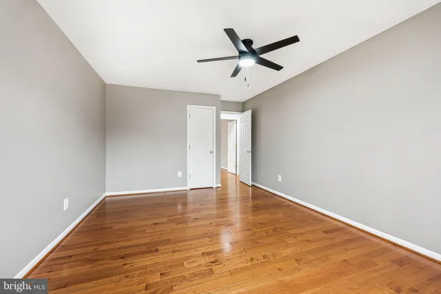 a view of an empty room with window and wooden floor