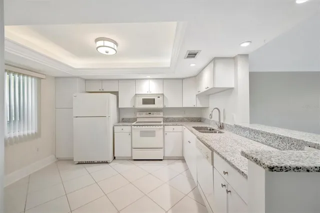 a kitchen with granite countertop appliances a sink and a refrigerator