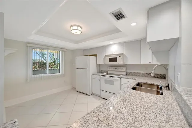 a kitchen with granite countertop white cabinets white stainless steel appliances with a sink and dishwasher