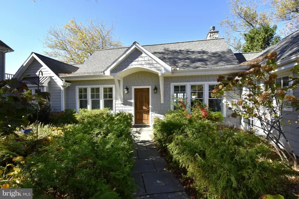 a view of a white house next to a yard with plants and trees