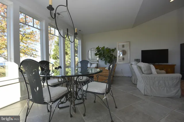 a dining room with furniture a chandelier and large windows