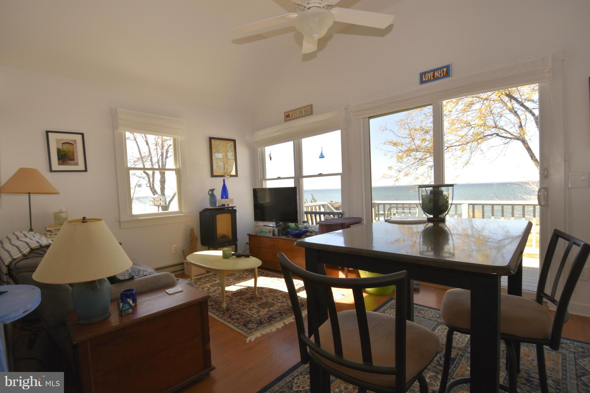 6050 Sunset Lane Tilghman, MD 21671 - Photo 52 of 74 a dining room with wooden floor a chandelier a glass table and chairs