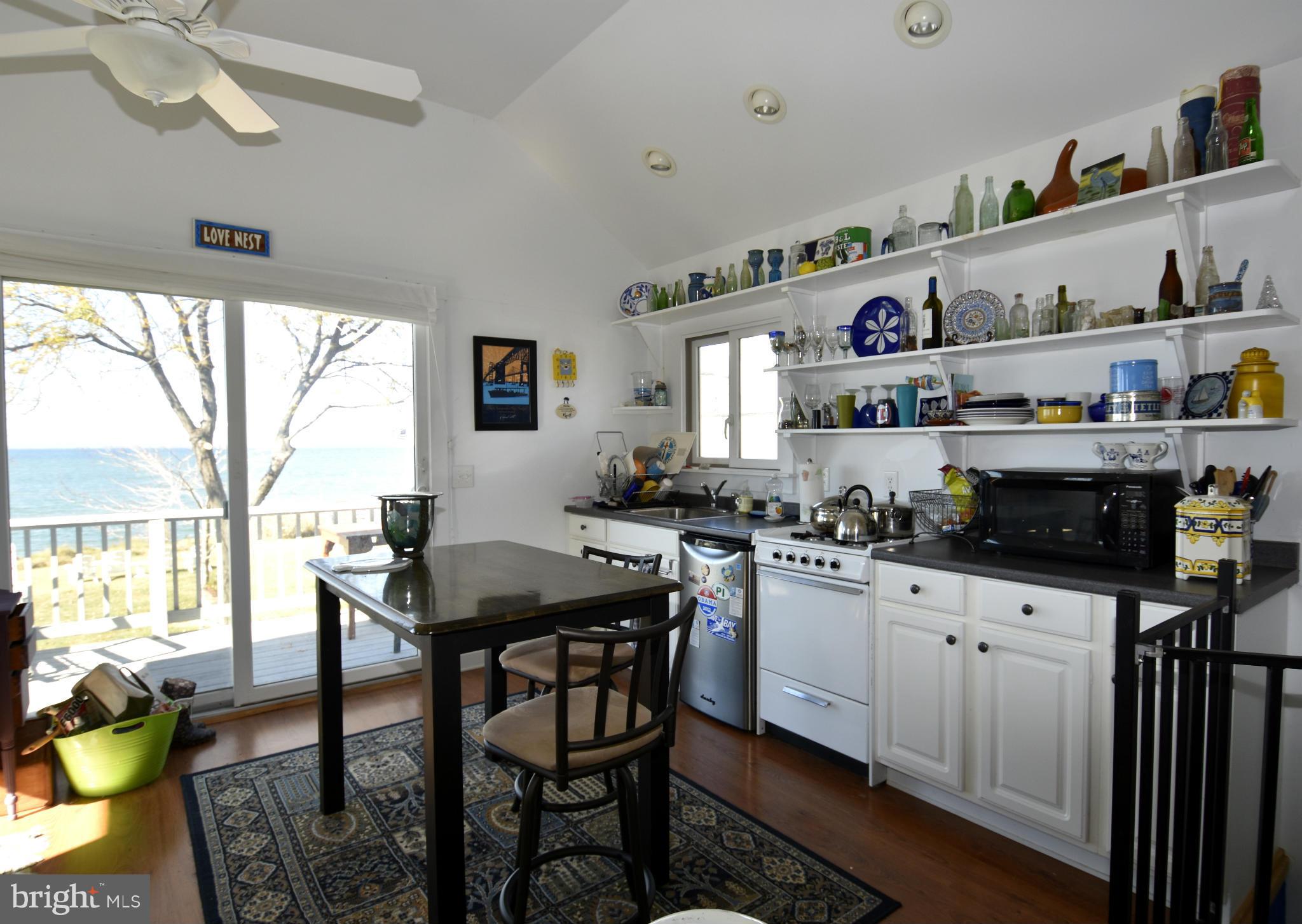6050 Sunset Lane Tilghman, MD 21671 - Photo 53 of 74 a kitchen with stainless steel appliances kitchen island granite countertop a table chairs in it and wooden floors