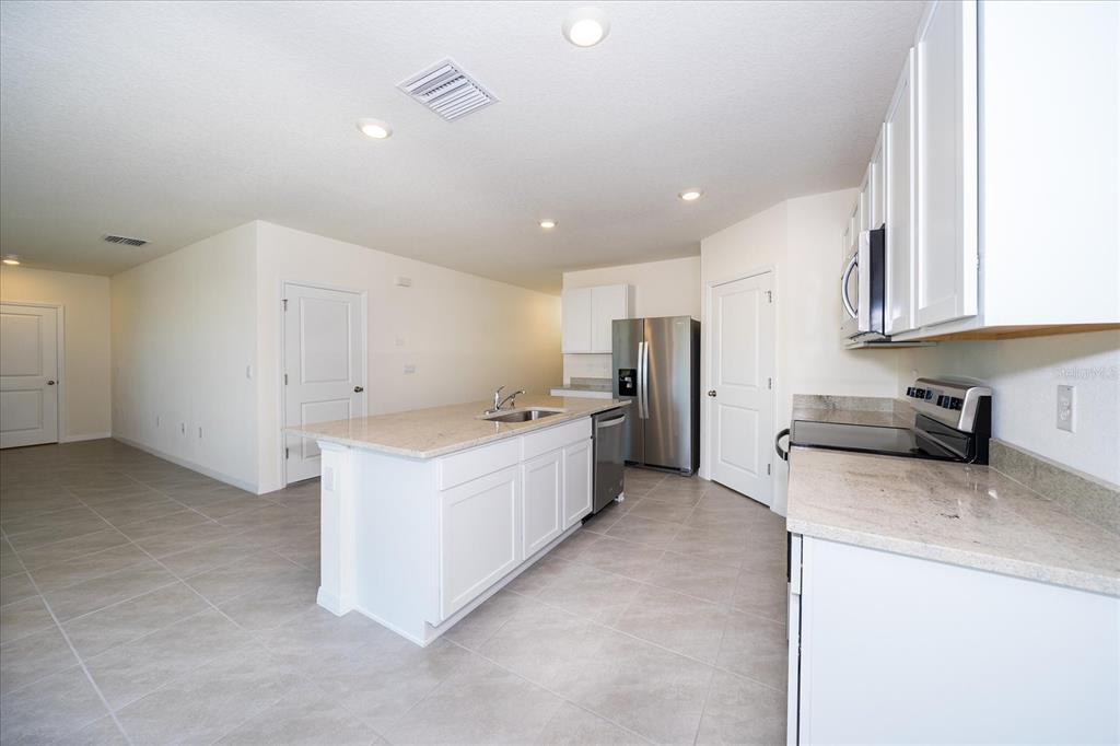31127 Penny Surf Loop Wesley Chapel, FL 33545 - Photo 11 of 33 a large kitchen with stainless steel appliances granite countertop a large counter top a sink a stove and a refrigerator
