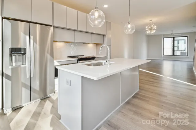 a kitchen with kitchen island granite countertop a refrigerator a stove a sink dishwasher and a dining table with wooden floor