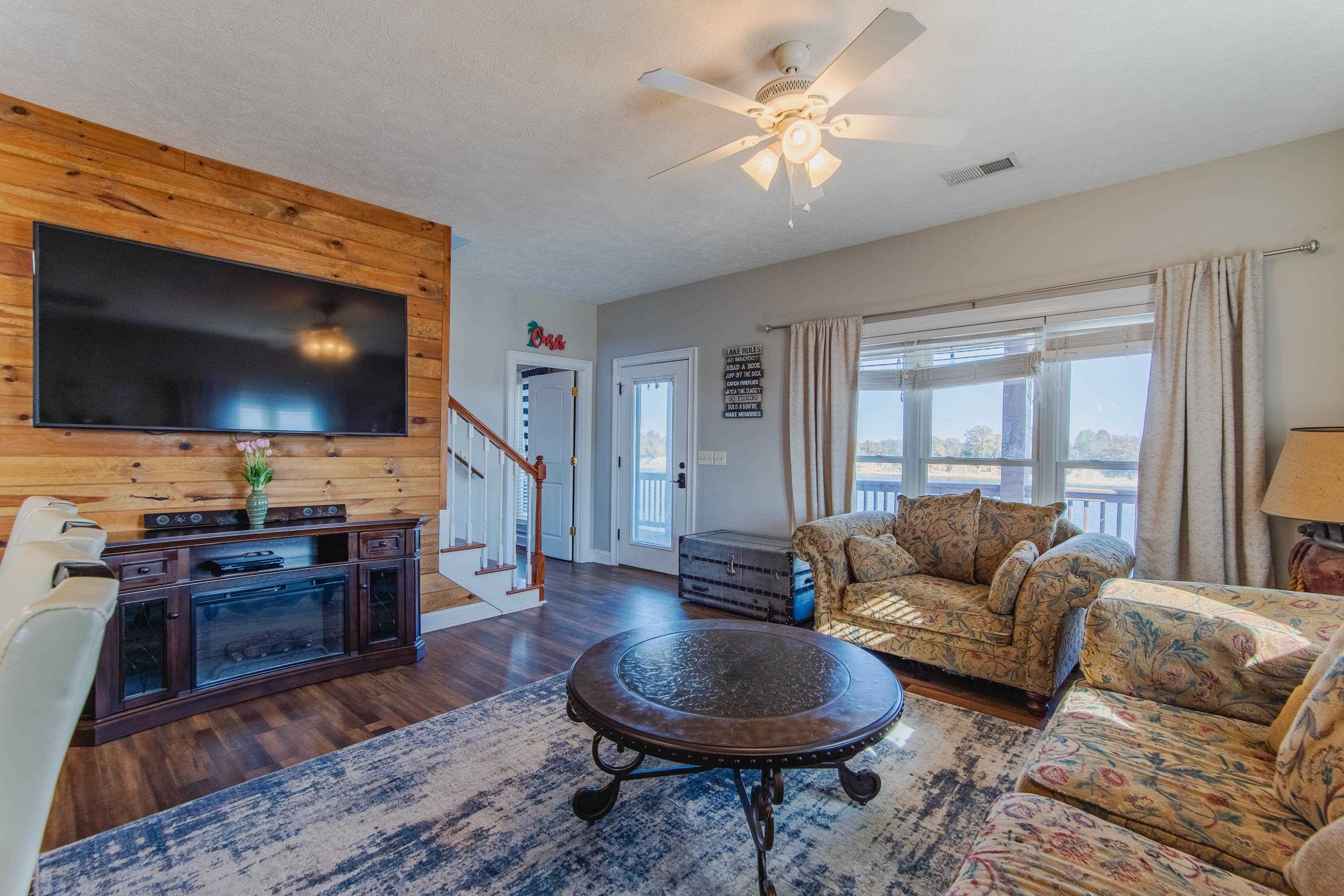 1111 Leaning Trees Lane Adamsville, TN 38310 - Photo 8 of 36 Living room featuring ceiling fan, wood walls, and dark hardwood / wood-style floors