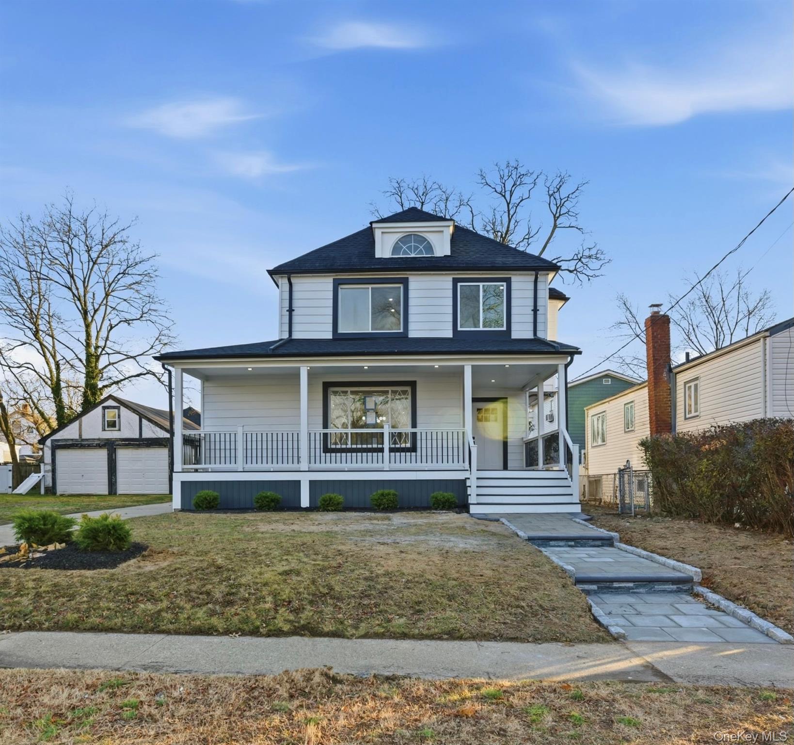 Traditional style home featuring a porch, an outdoor structure, a garage, and a front yard