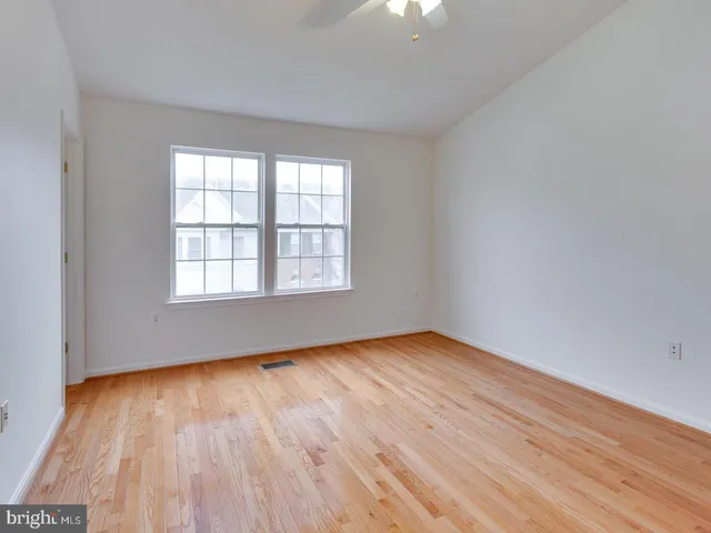 a view of a hallway with wooden floor and a bathroom