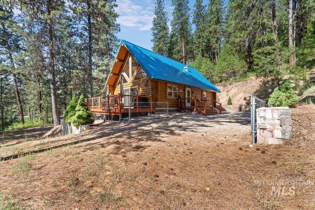 10 Elk Point Road Garden Valley, ID 83622 - Photo 41 of 42 View of side of property with log exterior, a wooden deck, a metal roof, and view of scattered trees