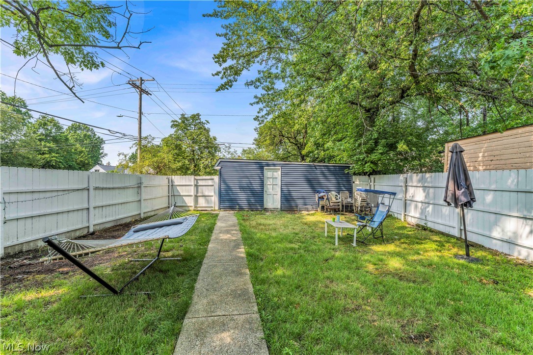3731 Lowell Road Cleveland Heights, OH 44121 - Photo 28 of 29 Fenced backyard featuring a concrete pathway, a detached storage shed with a white door, and mature trees providing natural shade