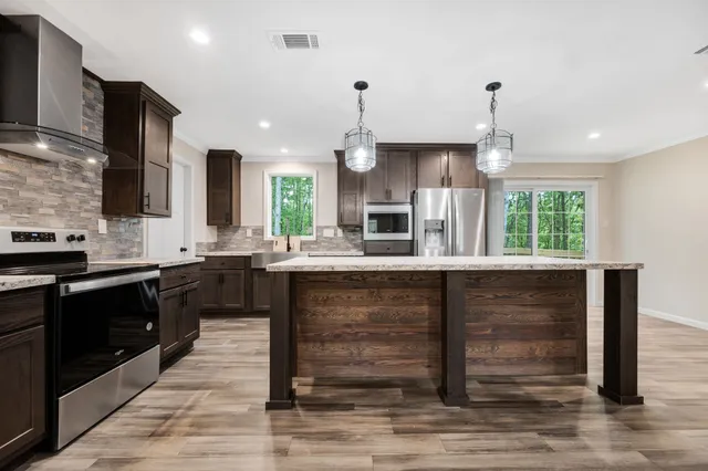 a kitchen with kitchen island granite countertop a sink appliances cabinets and a counter top space