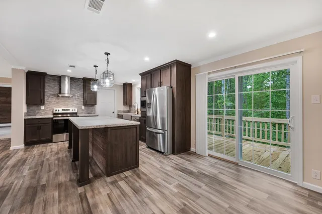 a kitchen with stainless steel appliances granite countertop a refrigerator a sink a stove and a wooden floors