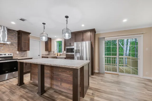 a kitchen with stainless steel appliances granite countertop a sink a stove and a wooden floors