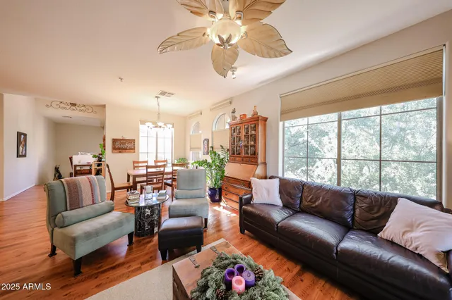 a living room with furniture ceiling fan and a large window