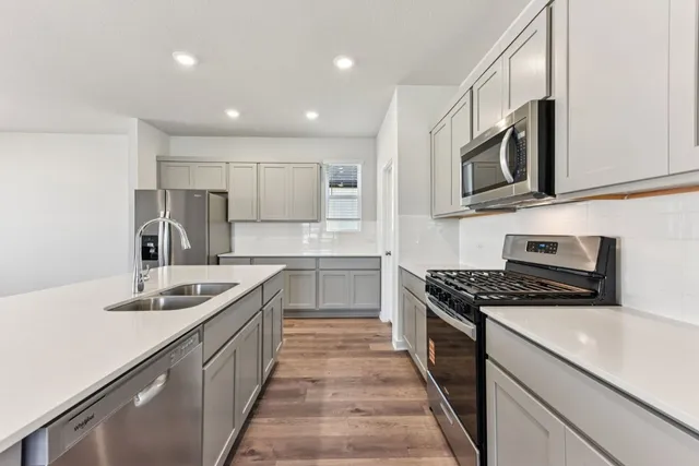 a large kitchen with stainless steel appliances a refrigerator and a stove top oven