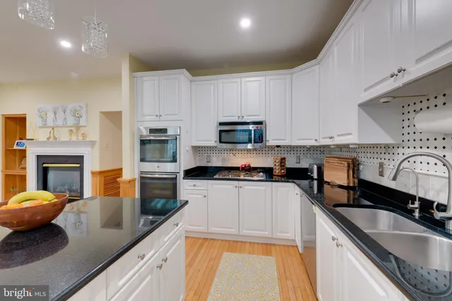 a kitchen with granite countertop a sink a stove top oven a counter space and cabinets