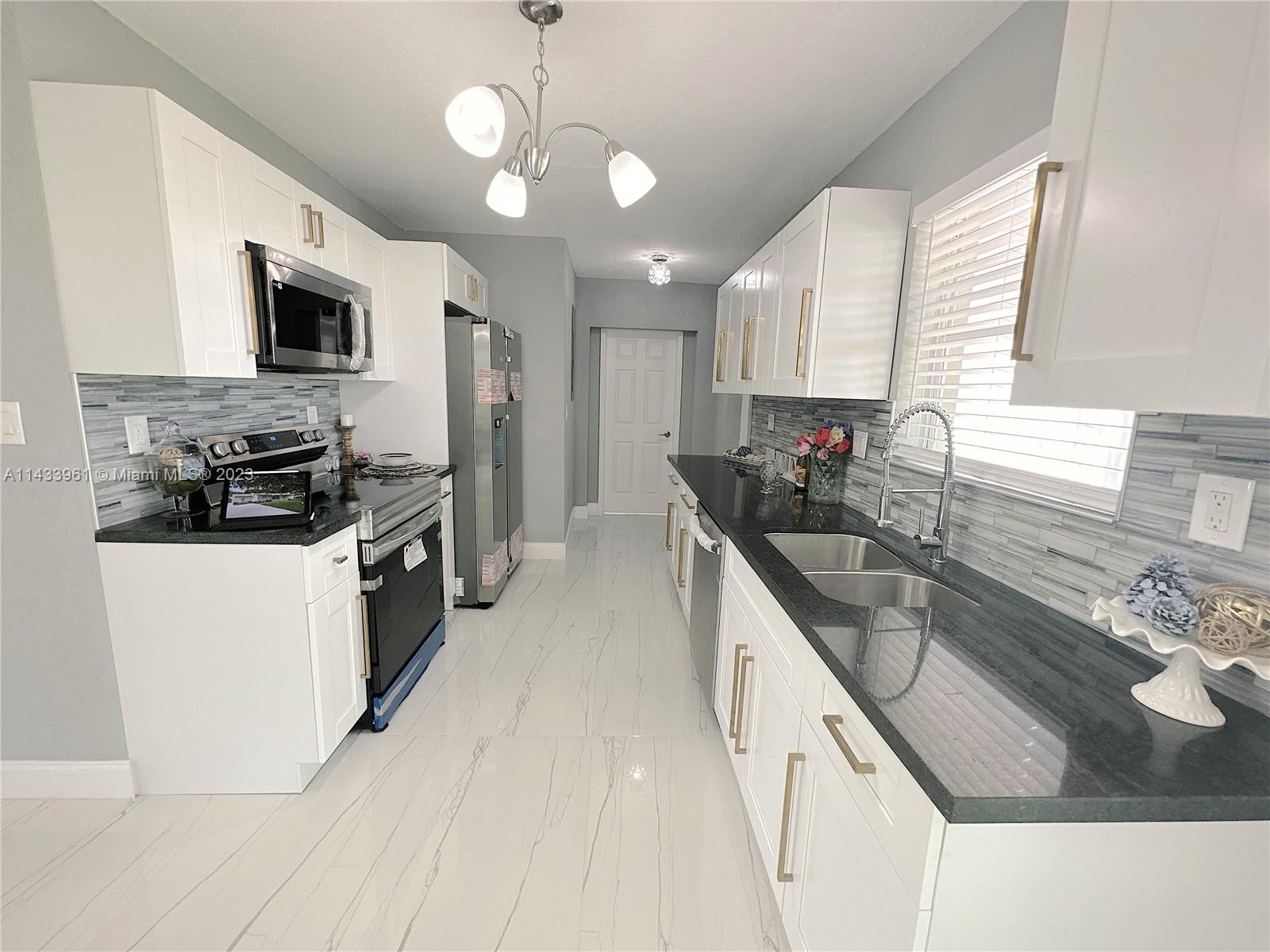 1460 Southwest 3rd Terrace Deerfield Beach, FL 33441 - Photo 24 of 100 a kitchen with stainless steel appliances granite countertop a sink stove and refrigerator