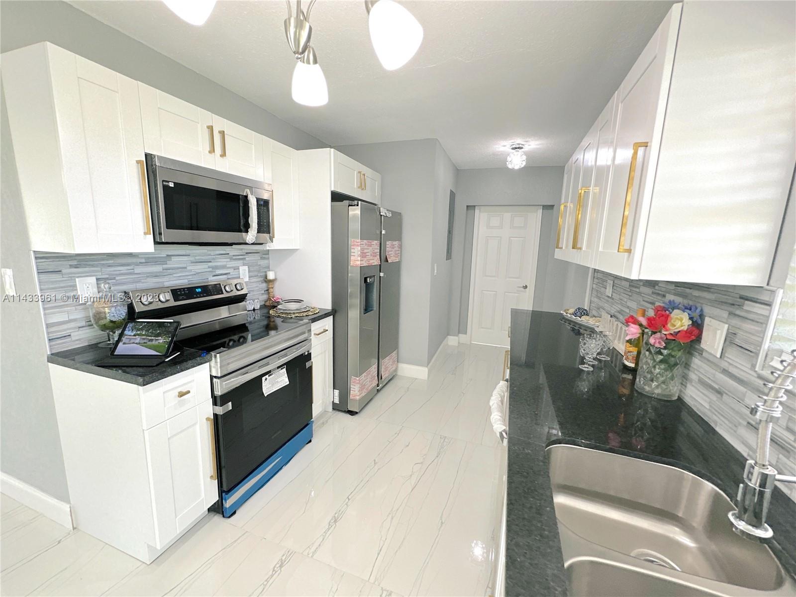 1460 Southwest 3rd Terrace Deerfield Beach, FL 33441 - Photo 26 of 100 a kitchen that has a lot of cabinets a sink and a stove in it