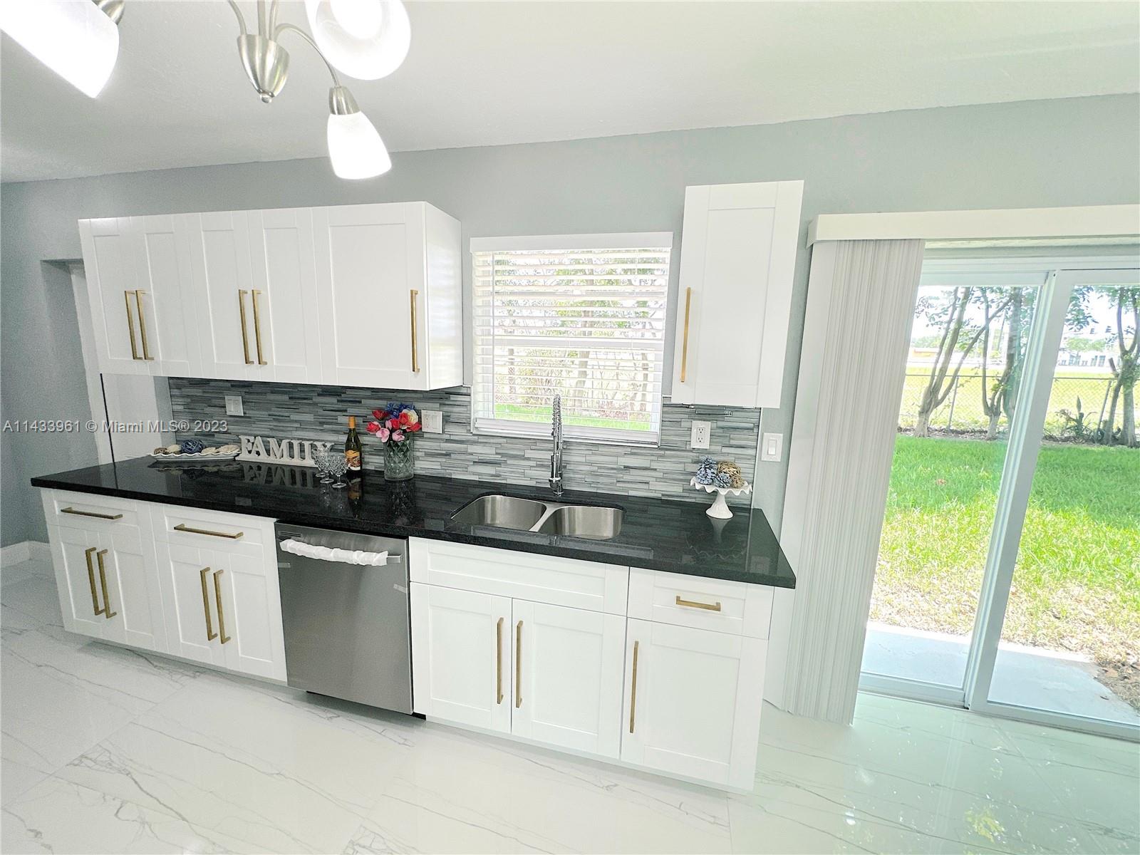 1460 Southwest 3rd Terrace Deerfield Beach, FL 33441 - Photo 28 of 100 a kitchen with granite countertop a sink and white cabinets
