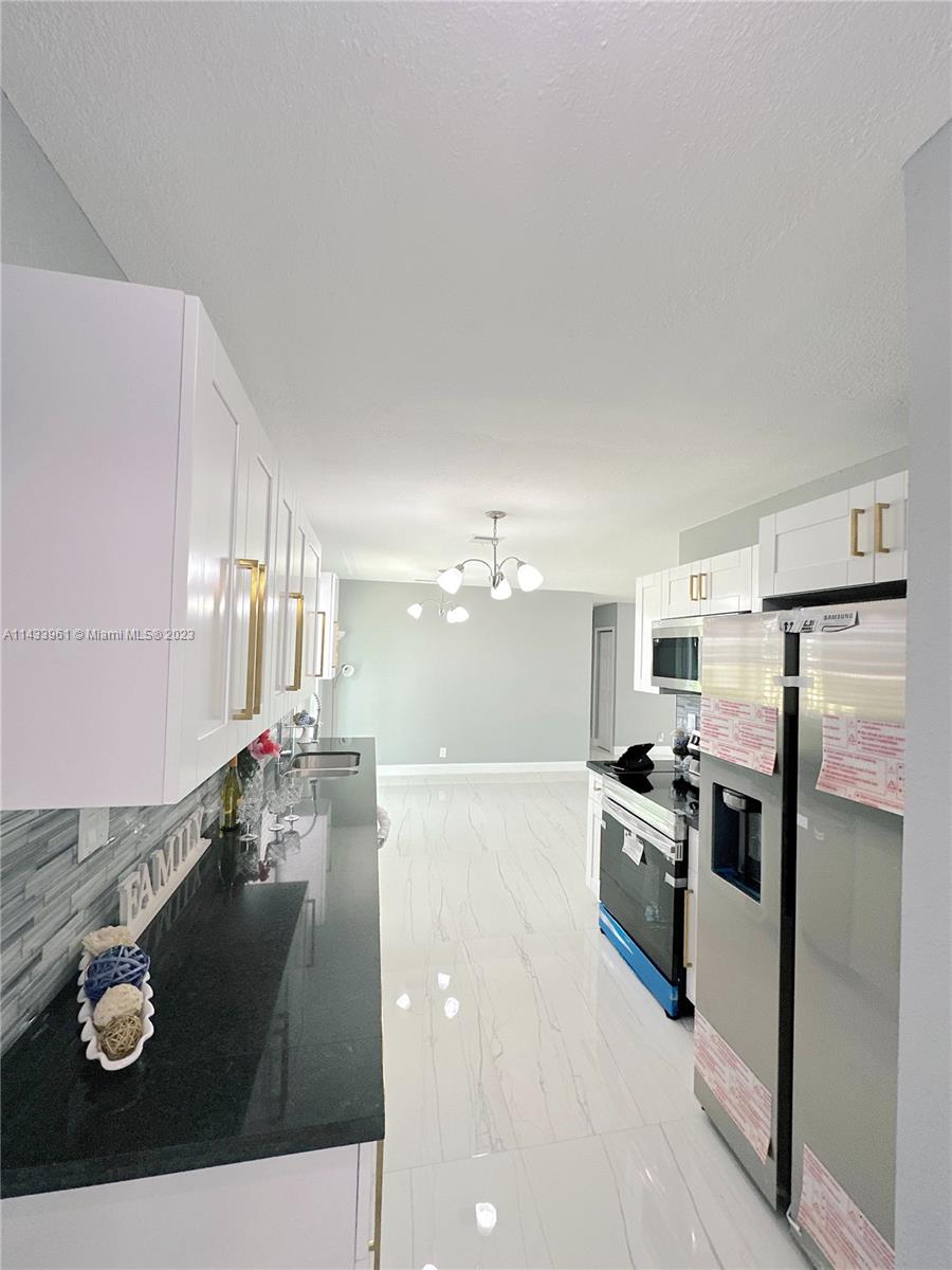 1460 Southwest 3rd Terrace Deerfield Beach, FL 33441 - Photo 30 of 100 a kitchen with stainless steel appliances granite countertop a sink a stove and a refrigerator