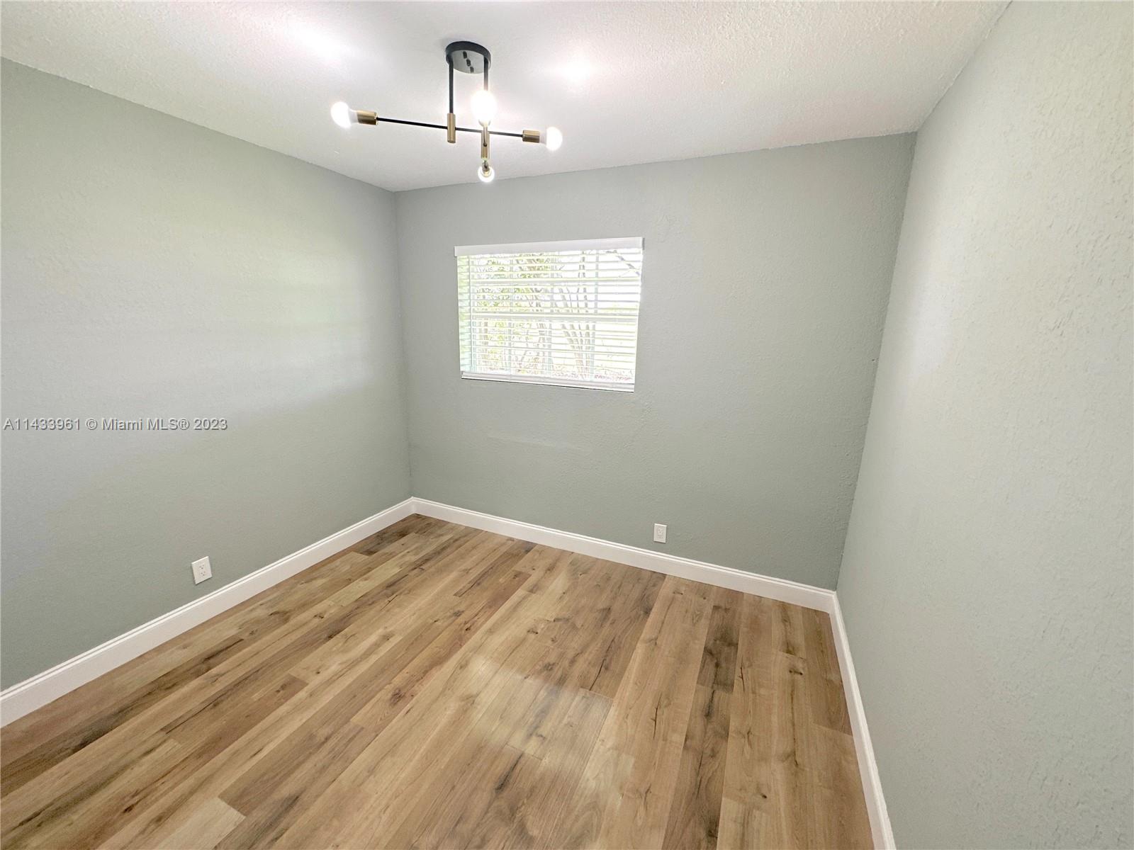 1460 Southwest 3rd Terrace Deerfield Beach, FL 33441 - Photo 59 of 100 an empty room with a chandelier fan and wooden floor