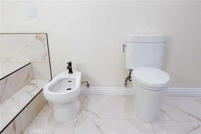 a white toilet sitting next to a bathroom sink and a mirror