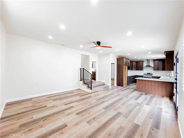 a view of a kitchen with kitchen island a sink stainless steel appliances counter space and wooden floor