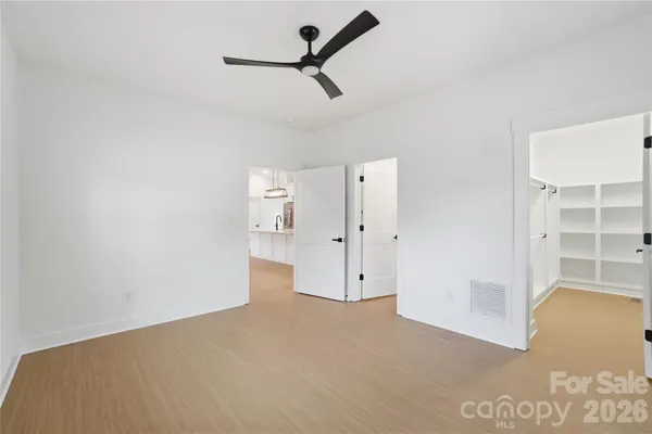 a view of empty room with wooden floor and ceiling fan